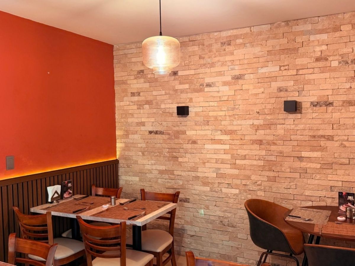 Mesas de la cafetería junto al muro de piedra y la pared roja