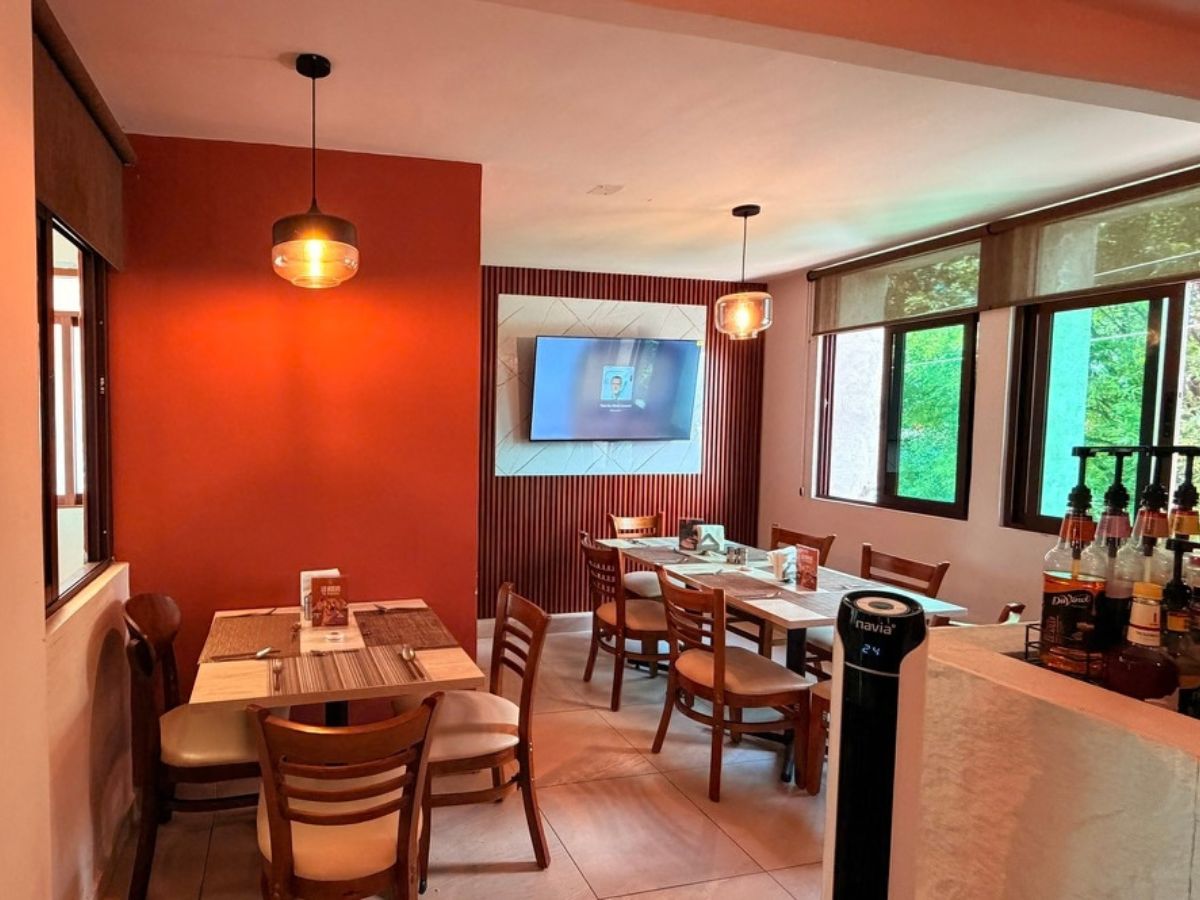 Salón de la cafetería con lámparas cálidas, mesas y televisión