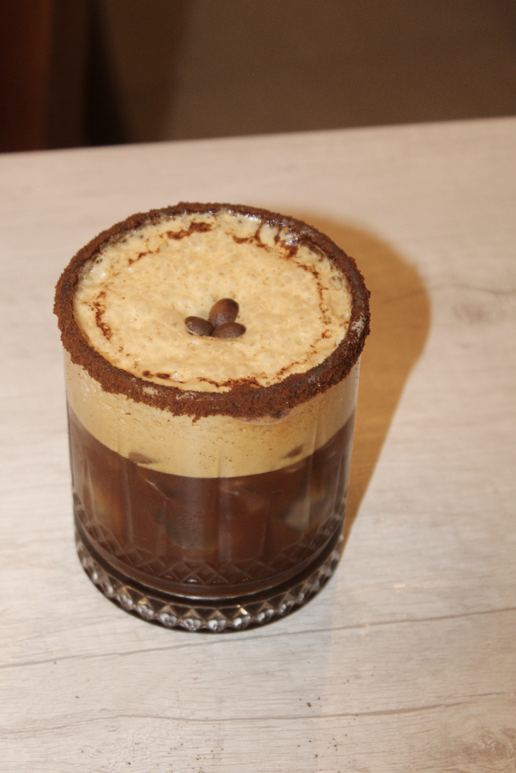 Carajillo de espresso con hielo, espuma de crema y granos de café