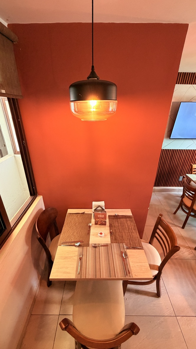 Mesa para cuatro personas bajo una lámpara frente a la pared roja